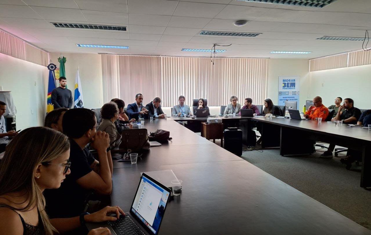 Pessoas com notebooks em reunião sentadas em torno de mesa com formato em U